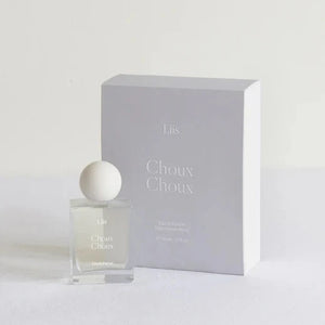 A bottle of Liis Eau de Parfum - Choux Choux, with a clear glass enclosure and a white cap, displayed in front of its grey box.