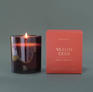 Candle with a lit wick and its packaging on a gray background
