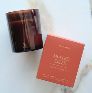 Brown candle and red box labeled 'Mulled Cider' on a marble surface