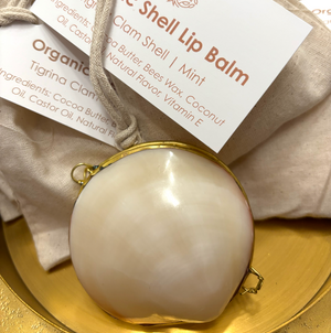 Organic shell lip balm with packaging on a gold plate