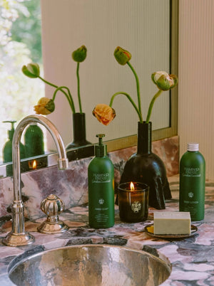 Flamingo Estate Garden Essentials Clary Sage hand soap, on a bathroom counter with poppies.