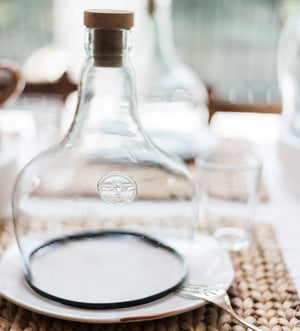 A glass cloche covering a plate at a table setting. 