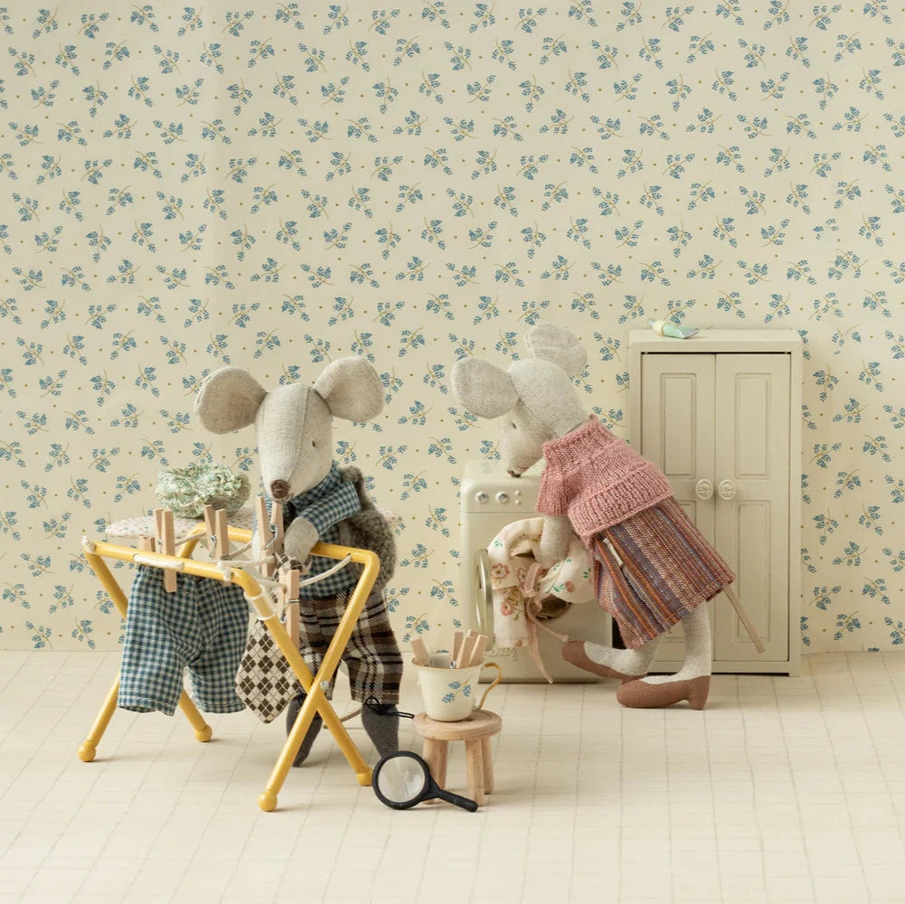 Two toy mice in a decorative room with floral wallpaper.