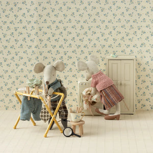 Two toy mice in a decorative room with floral wallpaper.