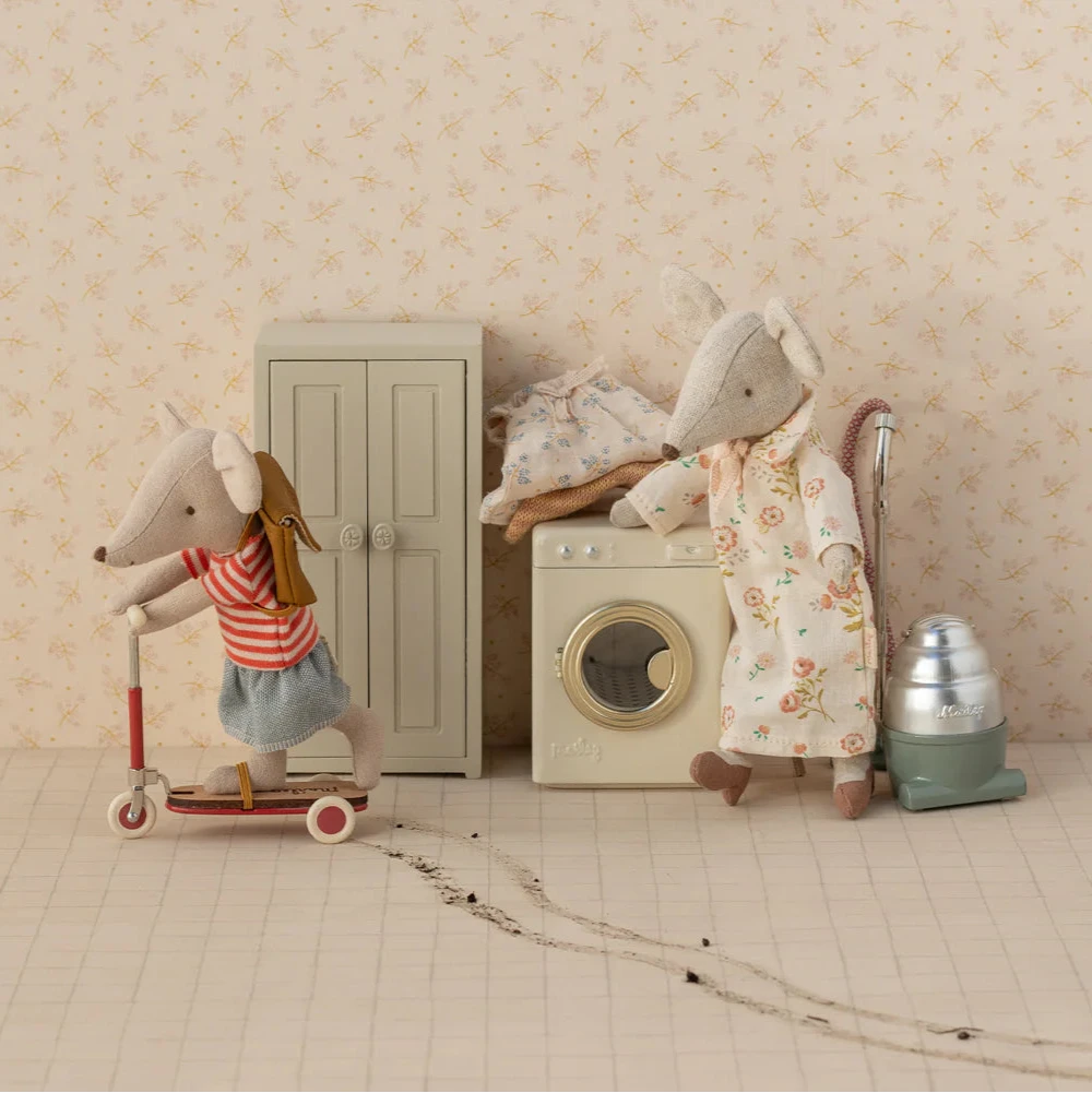Two toy mice in a home setting with a scooter and laundry machine.