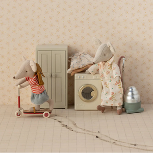 Two toy mice in a home setting with a scooter and laundry machine.