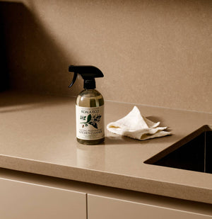 The Koala Eco Organic cotton cleaning cloth and the Koala Eco kitchen cleaner, on a light brown counter
