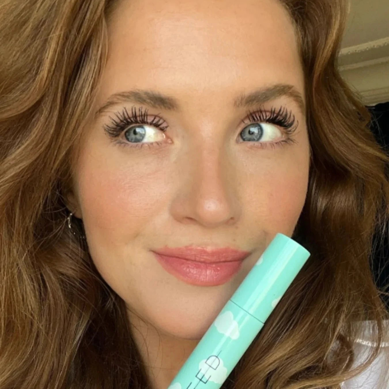 A woman holding a tube of Sweed Beauty Cloud mascara