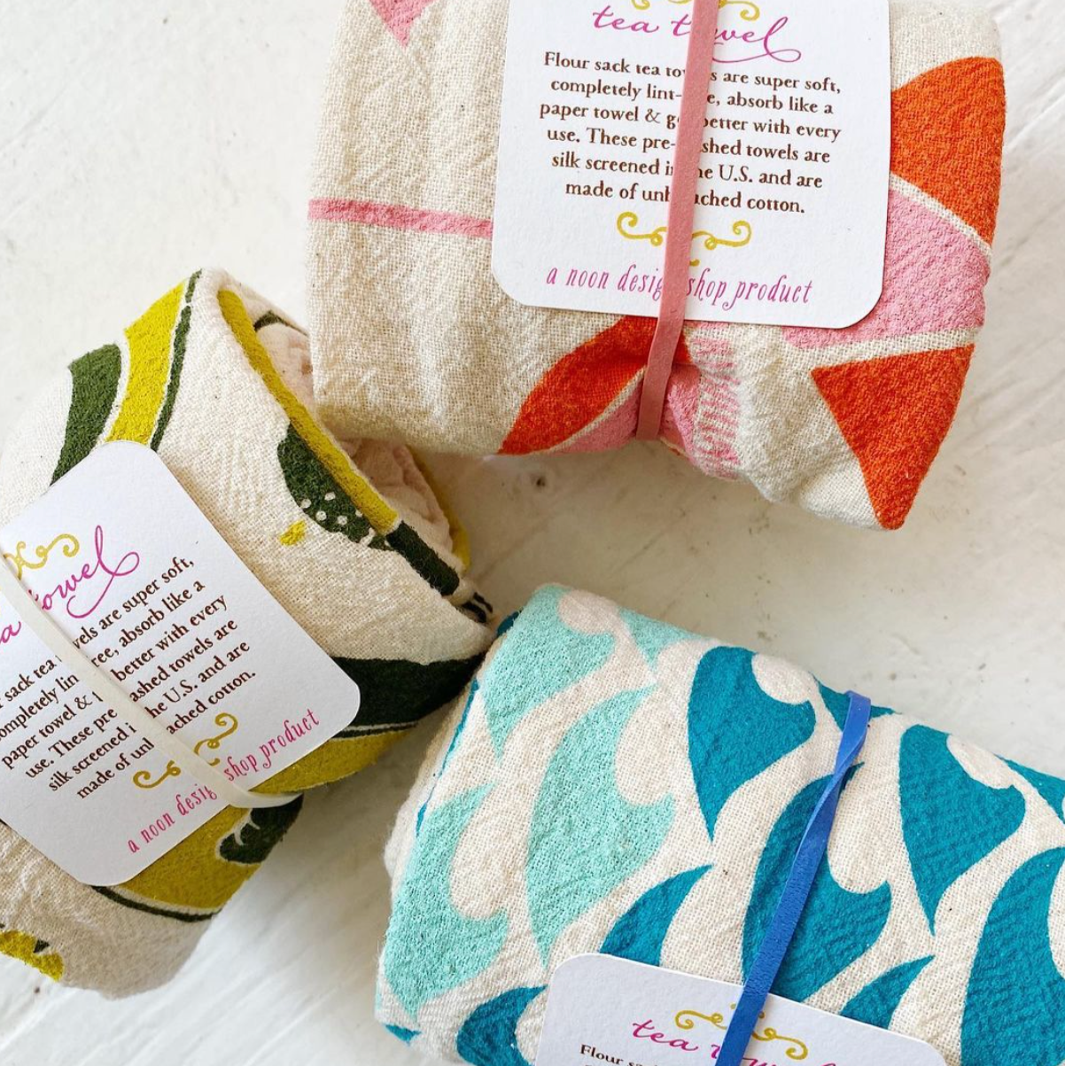 Three colorful tea towels, rolled up in balls. 