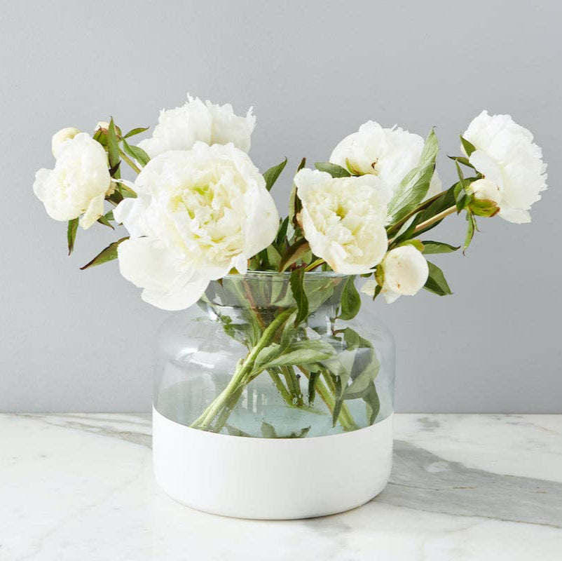 A white colorblock recycled glass vase with a wide mouth, standing on a marble surface.