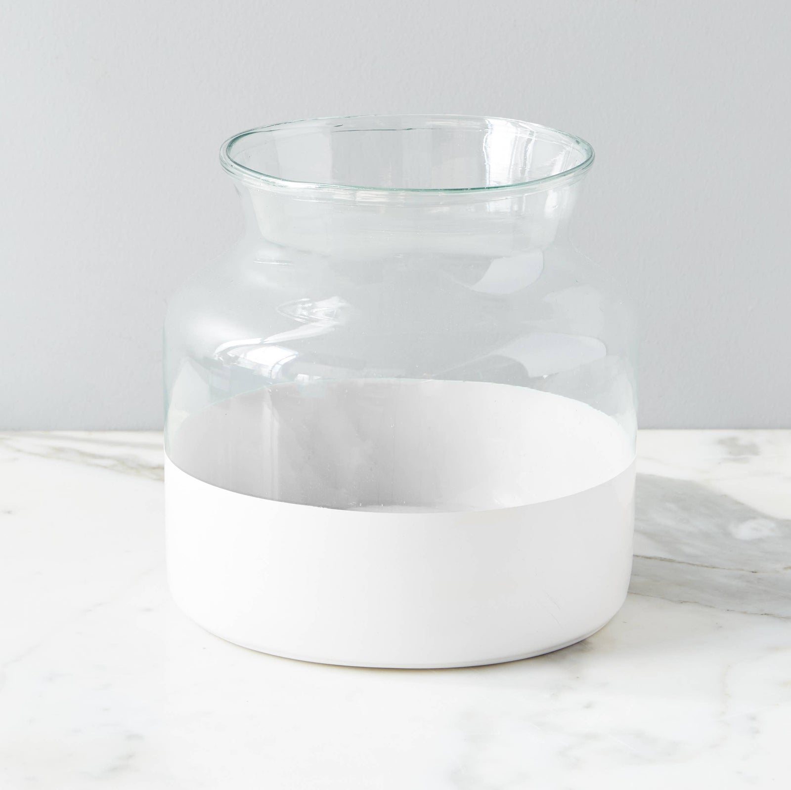 A white colorblock recycled glass vase with a wide mouth, standing on a marble surface.