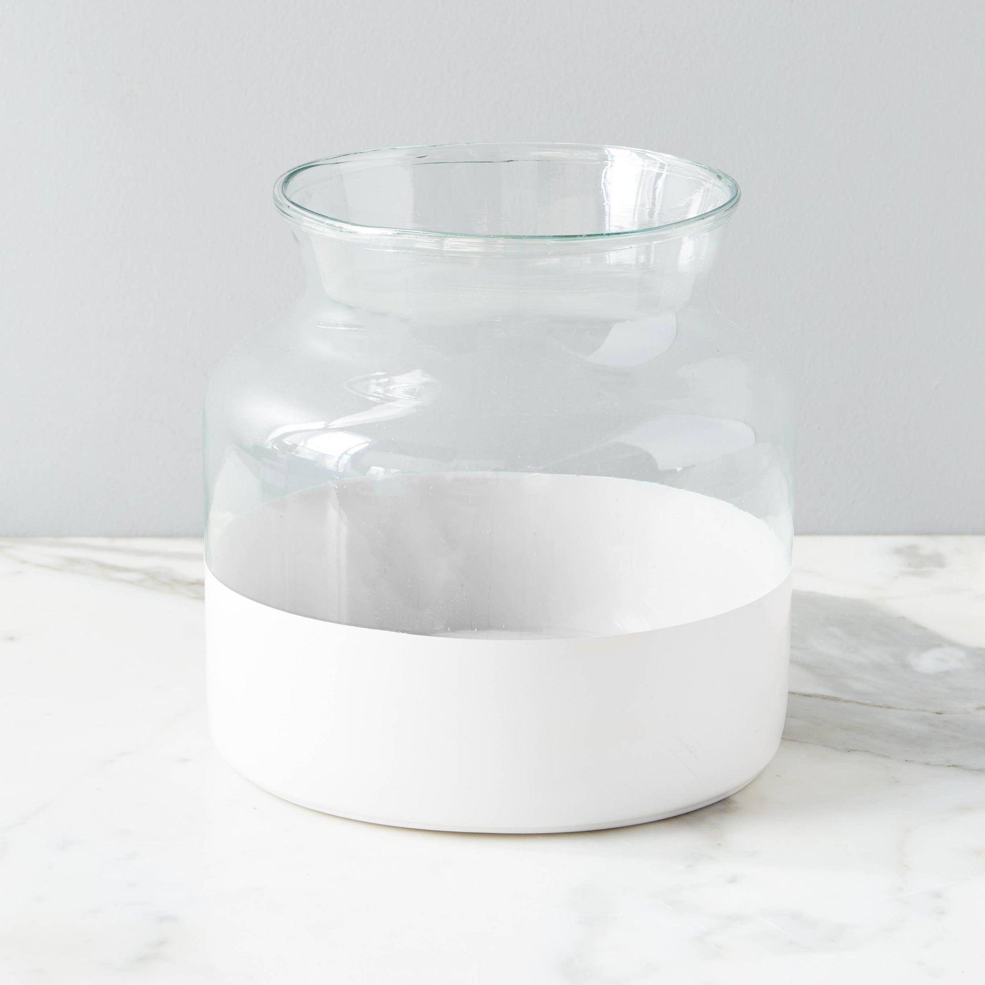 A white colorblock recycled glass vase with a wide mouth, standing on a marble surface.