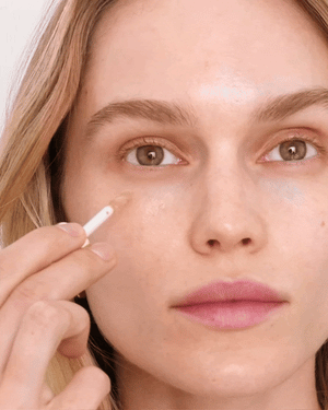 A woman applying concealer to her face