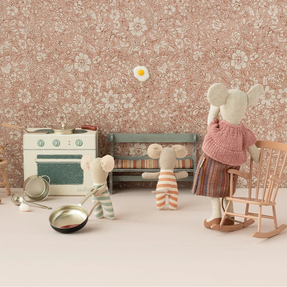 A small, toy kitchen set designed to look like a stove and oven with pretend food items and kitchen utensils on top, all packaged in a box with a floral pattern.