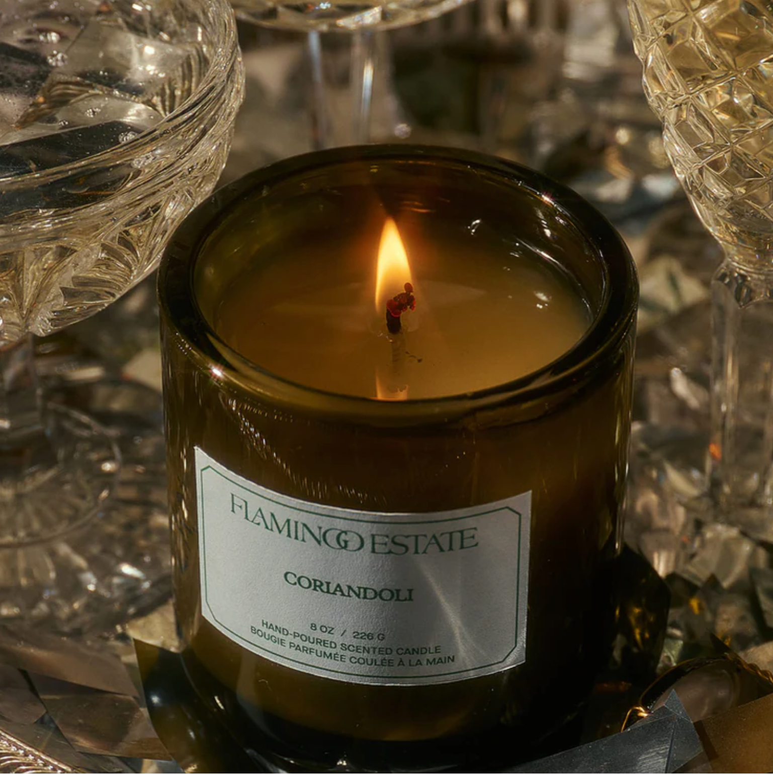 The Flamingo Estate Coriandoli candle, in a green glass vessel