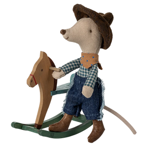 A plush toy mouse dressed as a cowboy, with a blue bandana, brown hat, and blue jeans, riding a small wooden rocking horse.