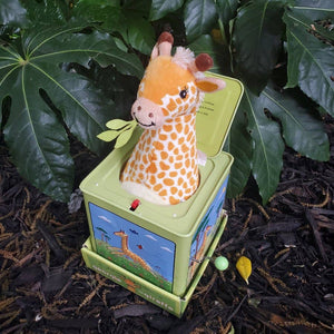Toy giraffe in a box with a leafy green background