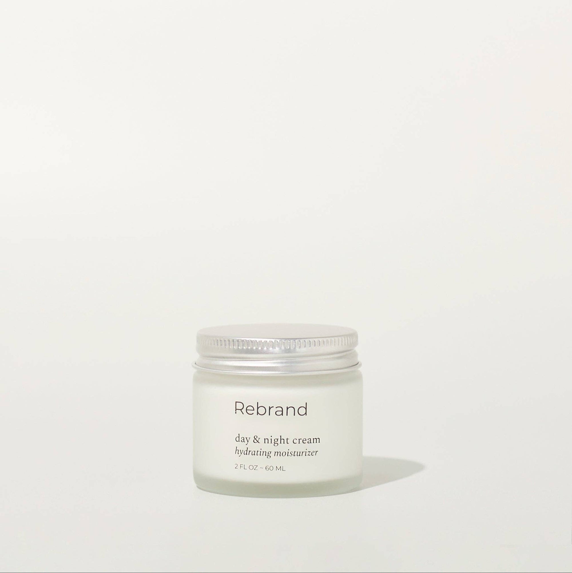 Hand holding a jar of Rebrand eye and night cream on a white background