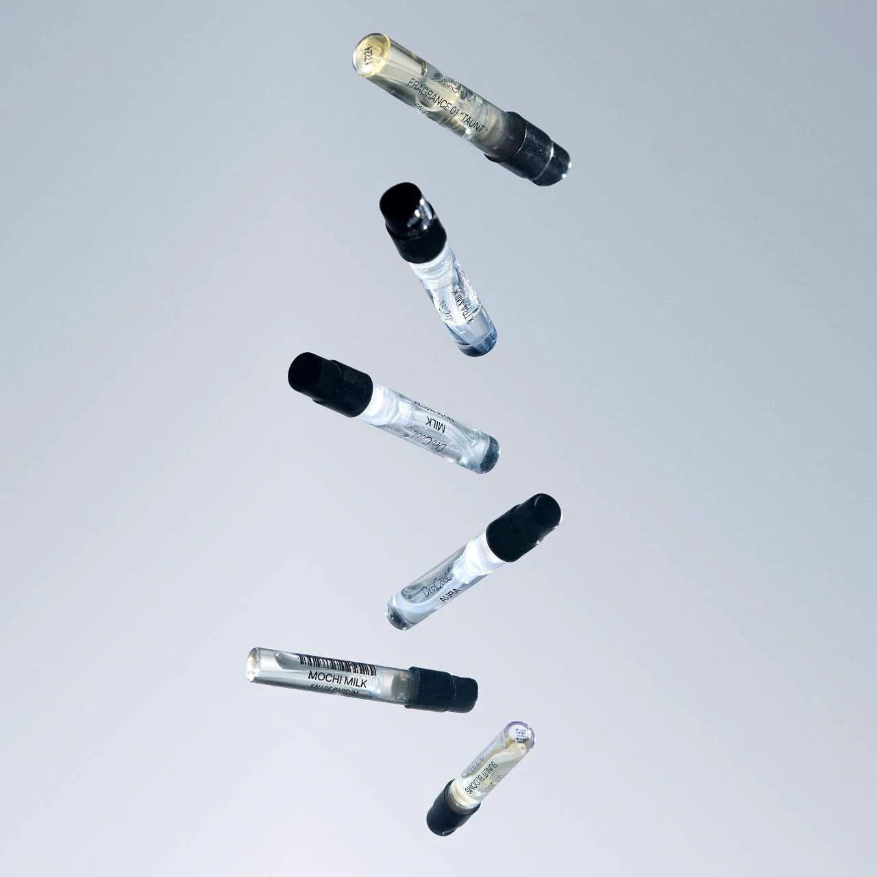 Set of glass vials with black caps on a light gray background