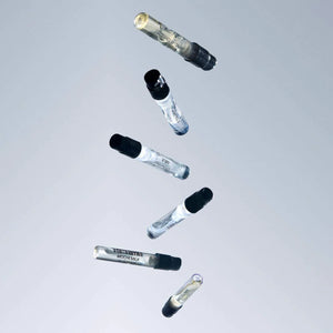 Set of glass vials with black caps on a light gray background