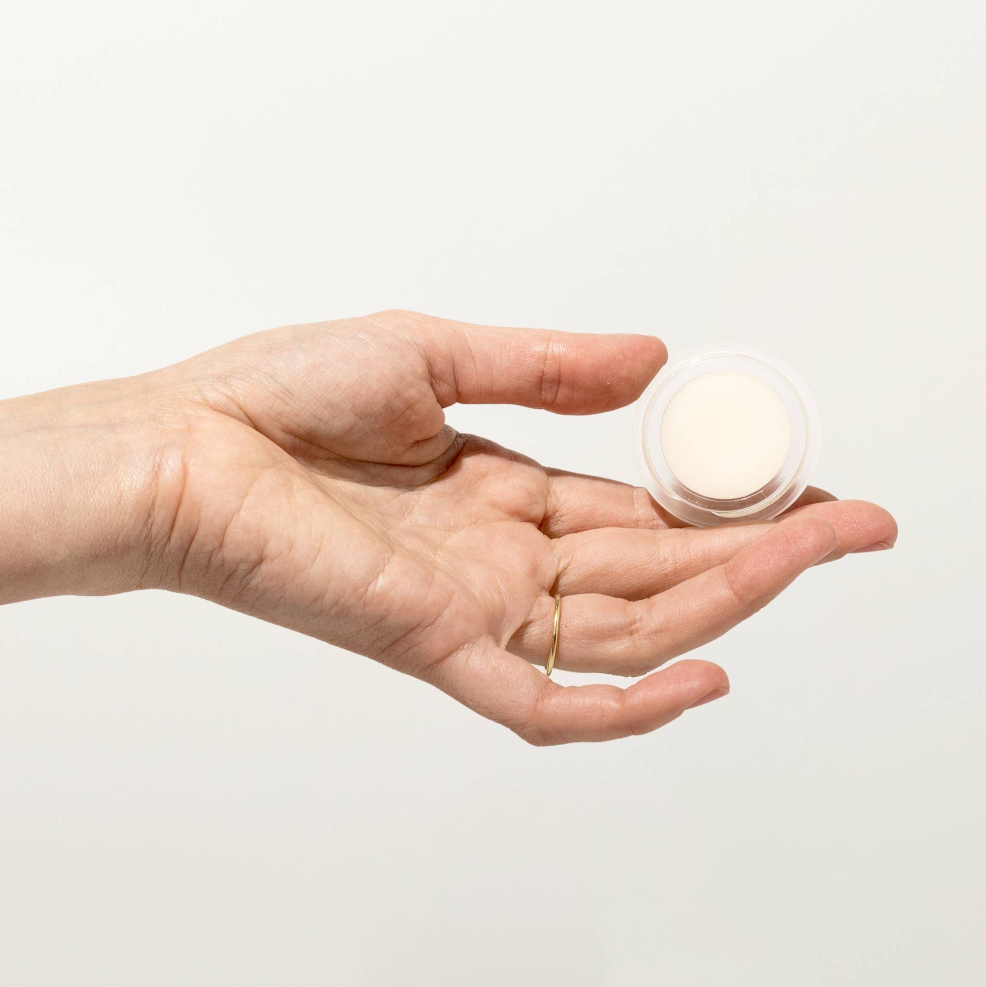 Silver jar of balm with 'Re' branding on a light beige background