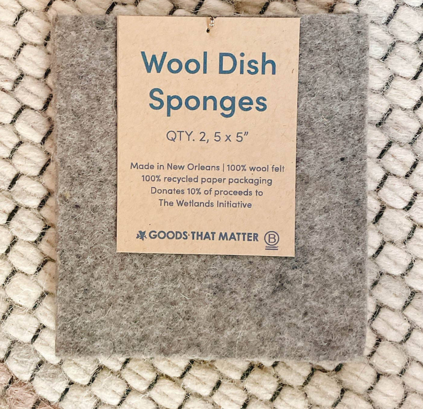 A wool dish sponge with a brown paper tag. 