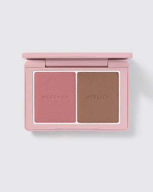 A Westman Atelier cheek powder duo featuring a deeper shade on one side and a lighter shade on the other, both with a matte finish.