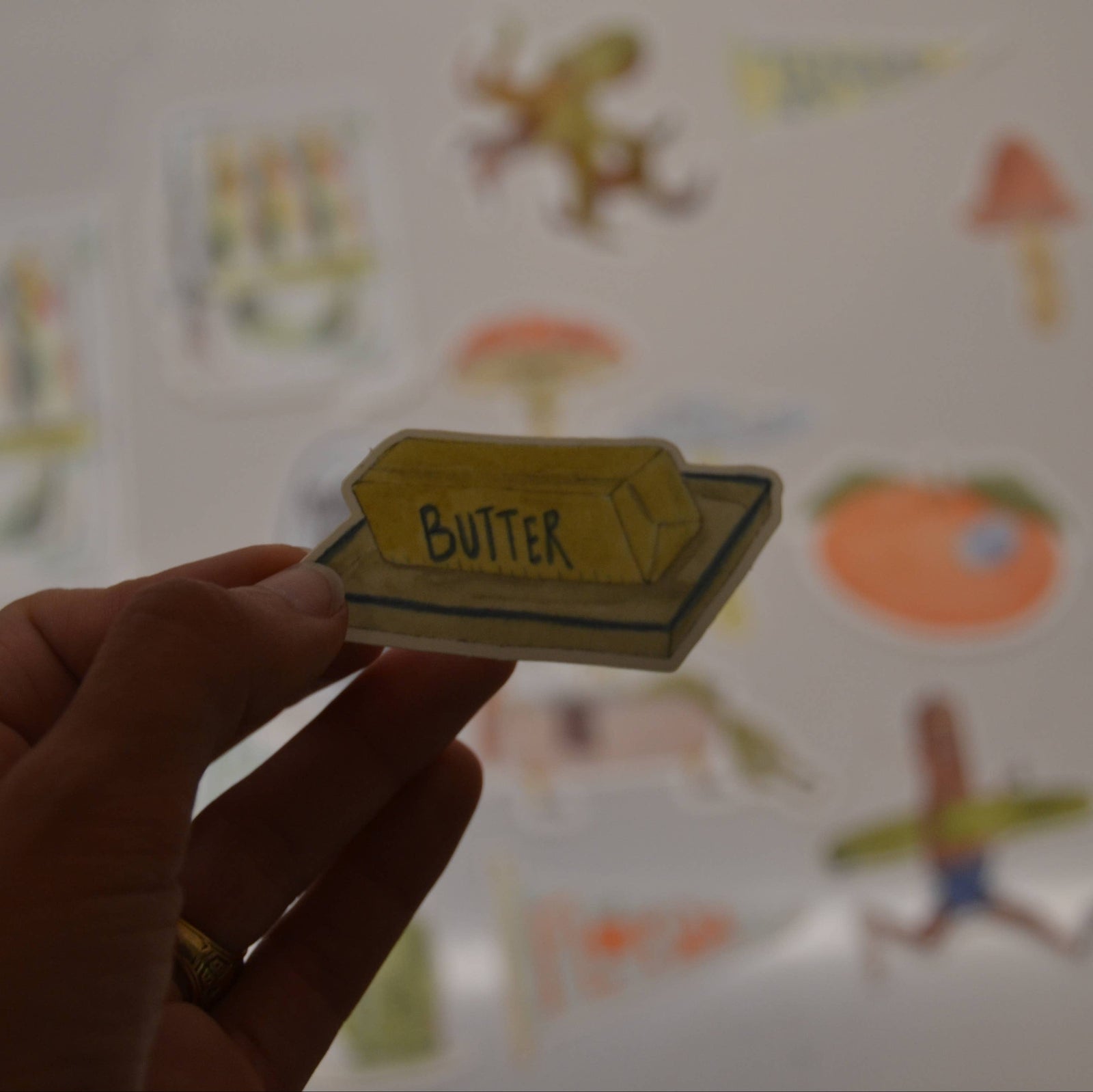 Hand holding a card labeled 'Butter' with colorful illustrations in the background
