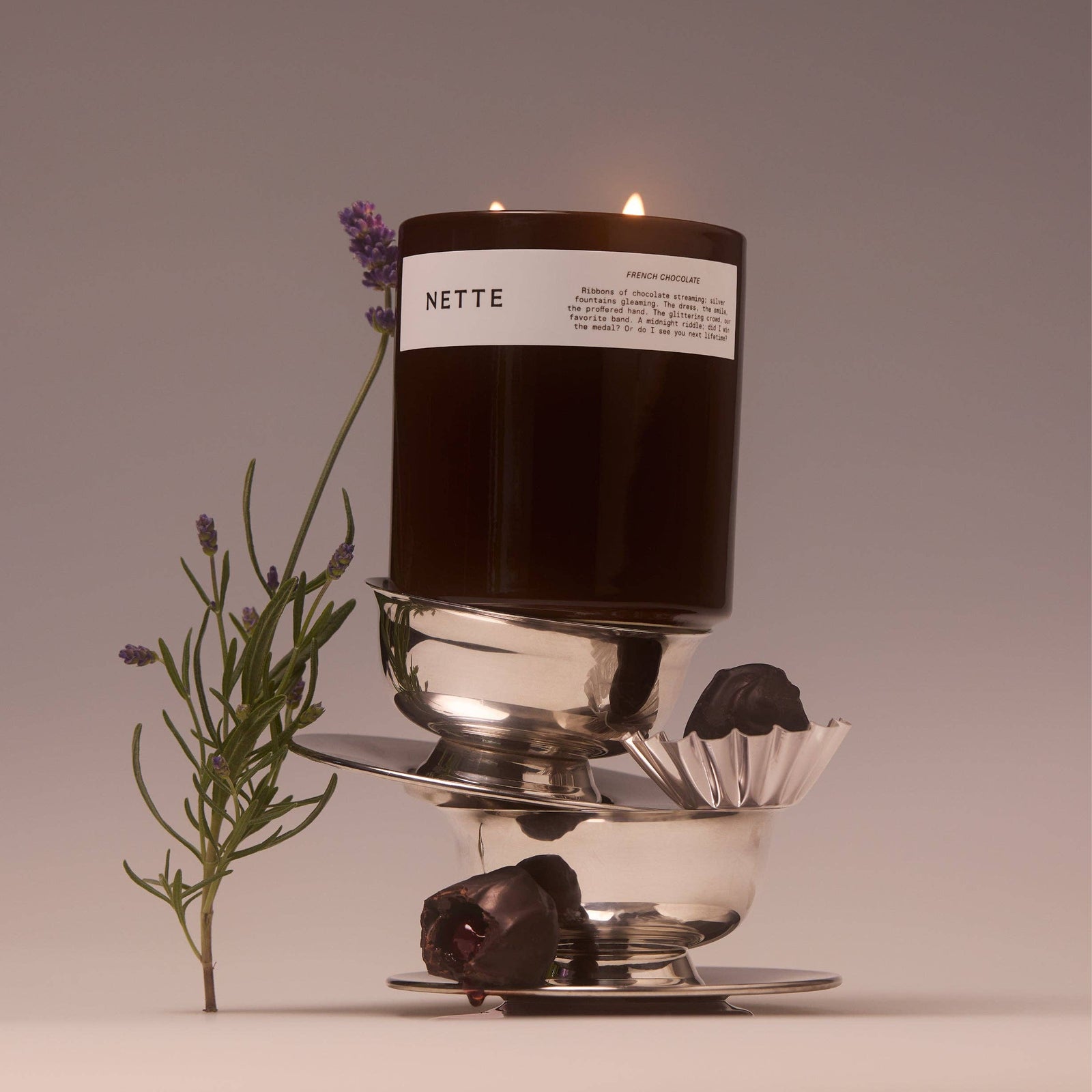 Black candle with a white label on a light beige background