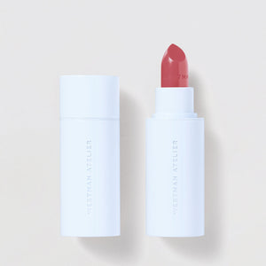 Lipstick with white casing and red shade on a light beige background