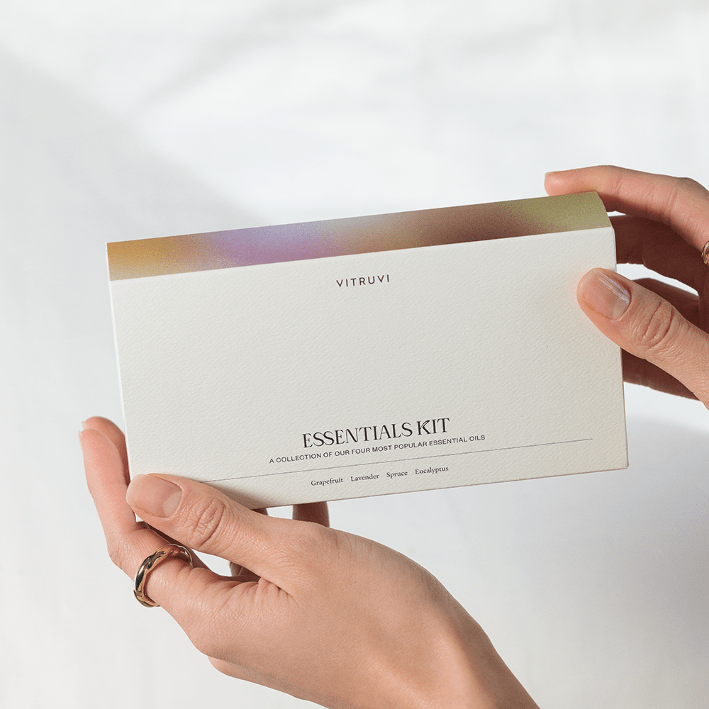 Four VITRUVI essential oil bottles on a green background