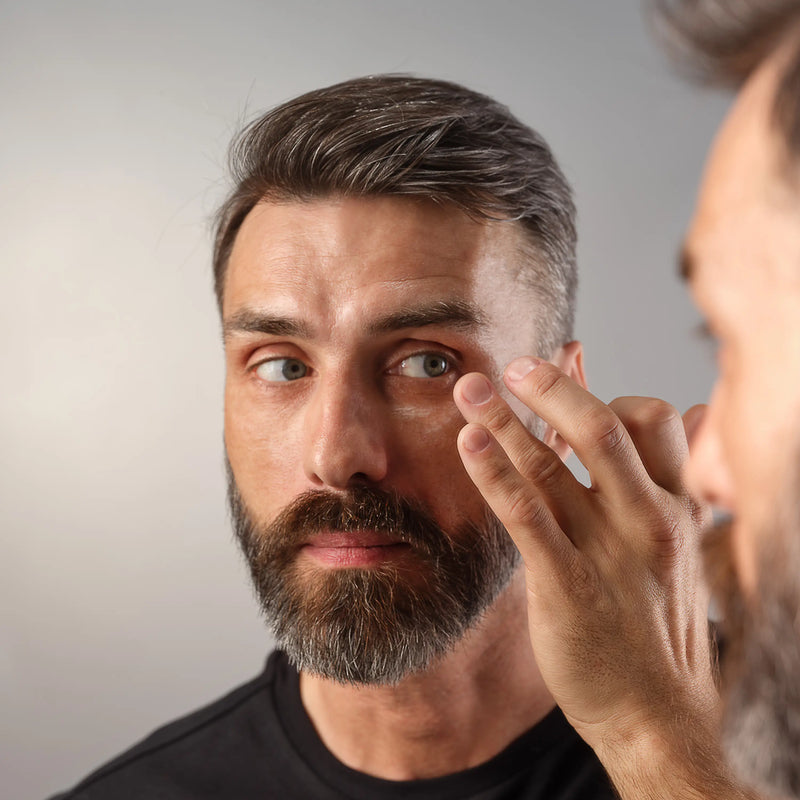 A man touching his hand to his eye. 