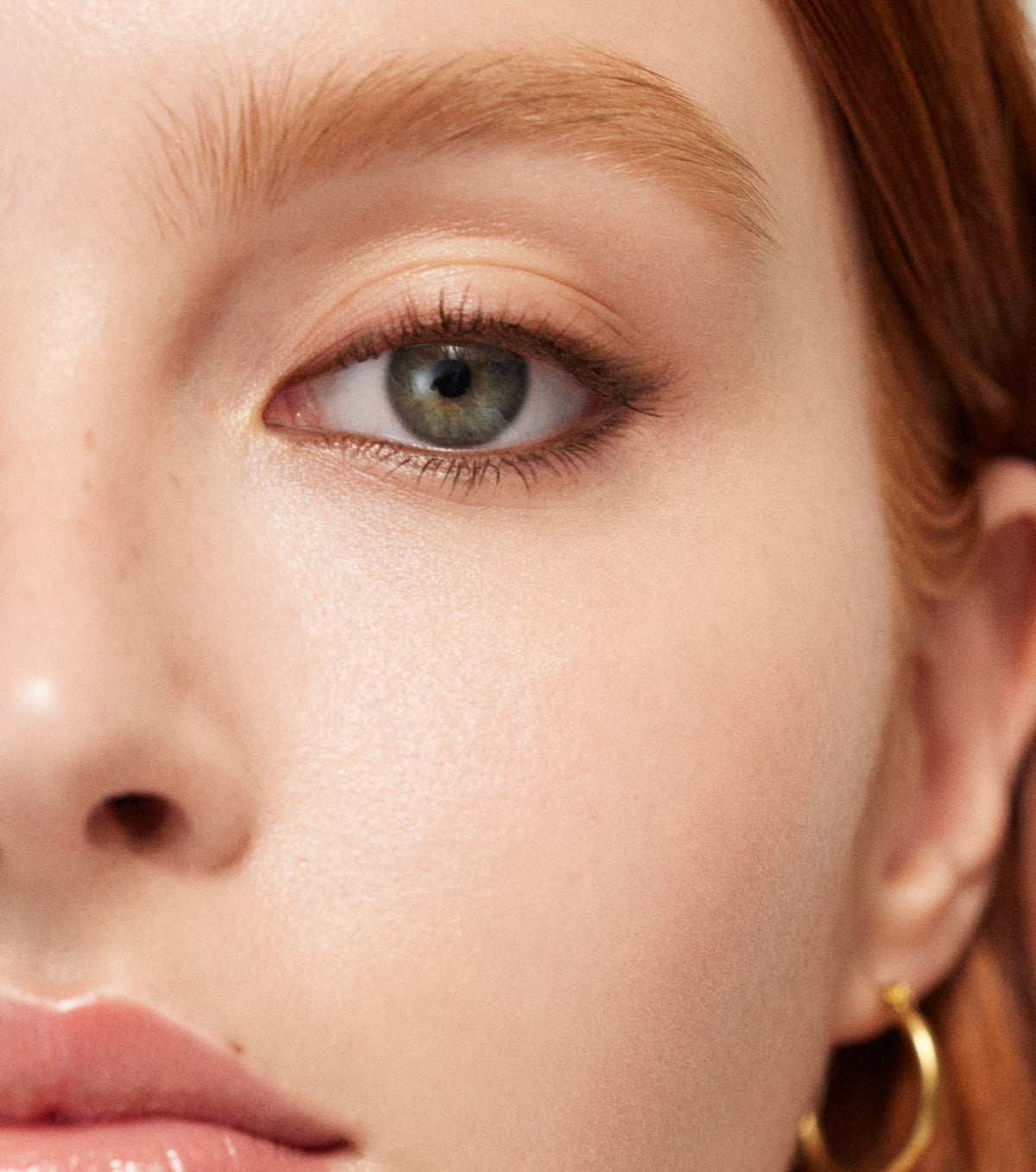 Close-up of a person's eye with makeup and a gold earring.