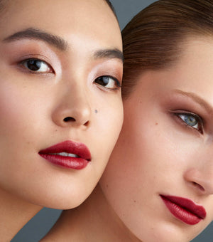 Two women with close-up faces, one with red lipstick and the other with a neutral expression.