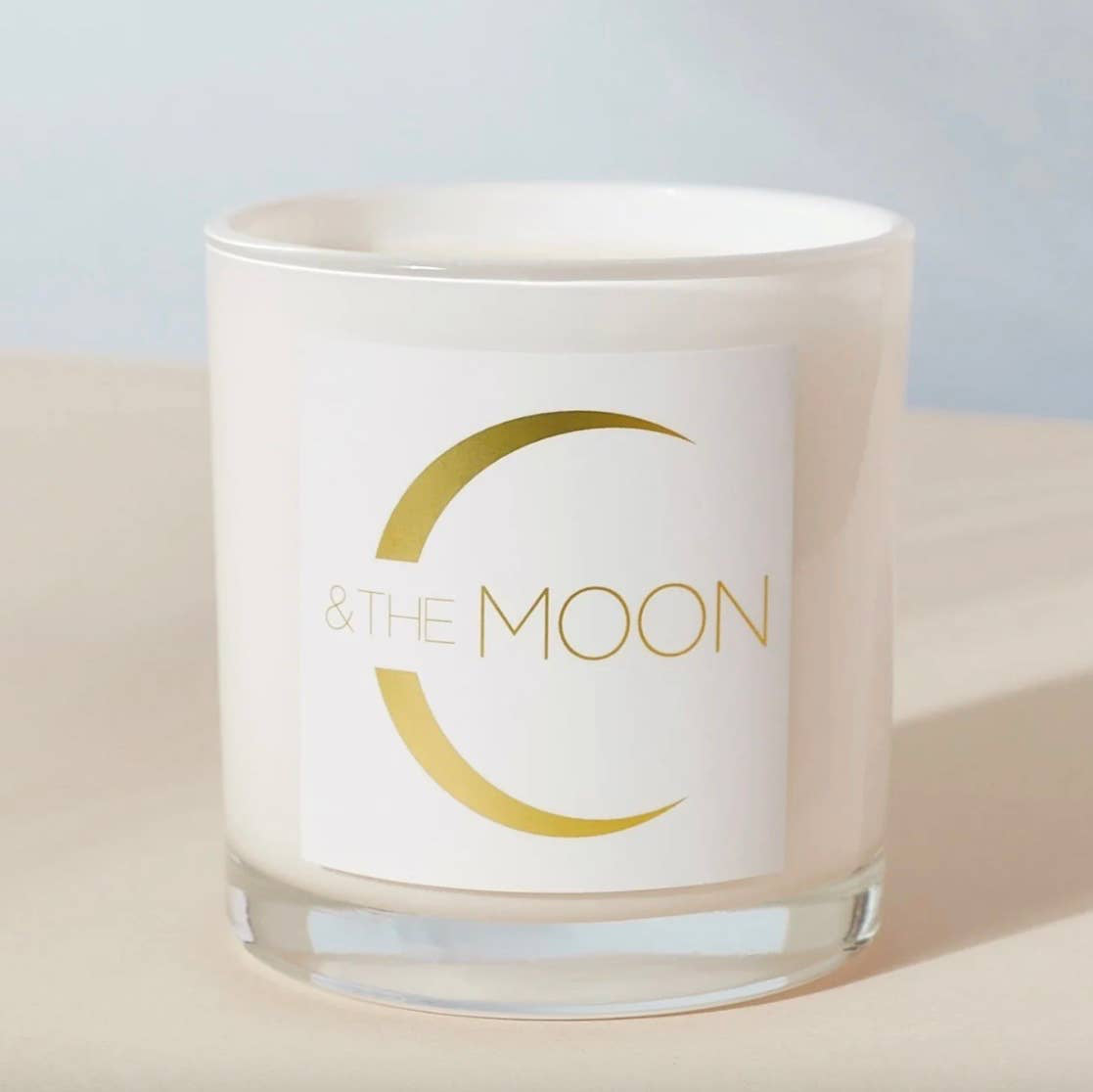 Candle in a glass jar with 'By the Moon' branding on a light background