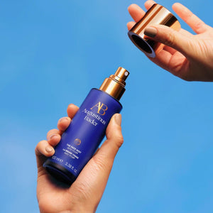 A person holding a bottle of The Face Mist in the air