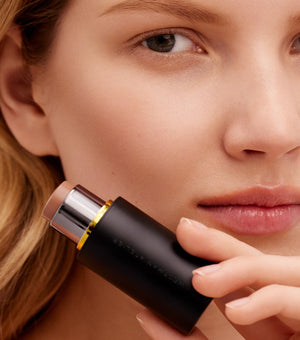 Woman holding a makeup stick close to her face