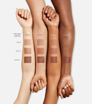 Four arms with swatches of foundation shades on a white background
