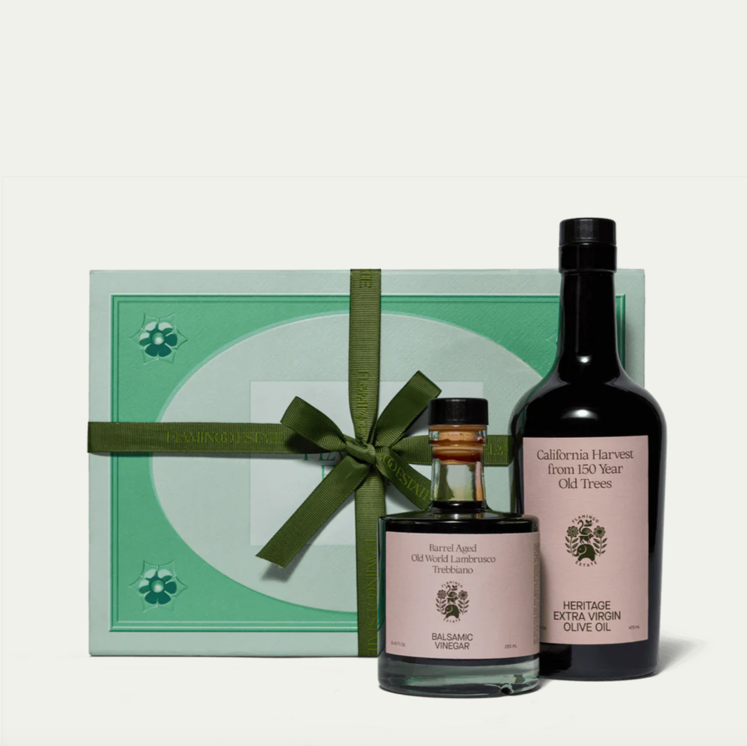 A gift set containing a bottle of olive oil and a smaller bottle of balsamic vinegar, packaged in a box tied with a green ribbon.
