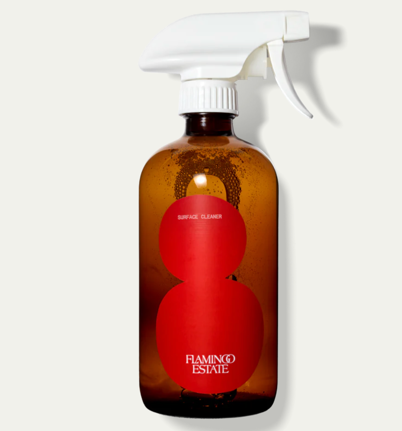 A brown glass bottle with a white spray nozzle, labeled with 'Flamingo Estate' and 'Surface Cleaner Roma Heirloom Tomato'.
