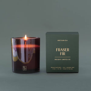 Lit candle and its packaging on a gray background