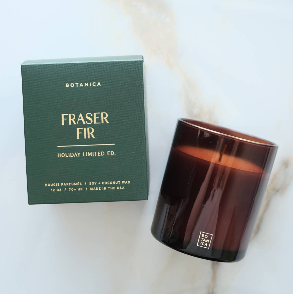 Lit candle and its packaging on a gray background