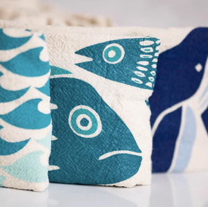 Blue and white tea towels with fish and waves printed on them. 
