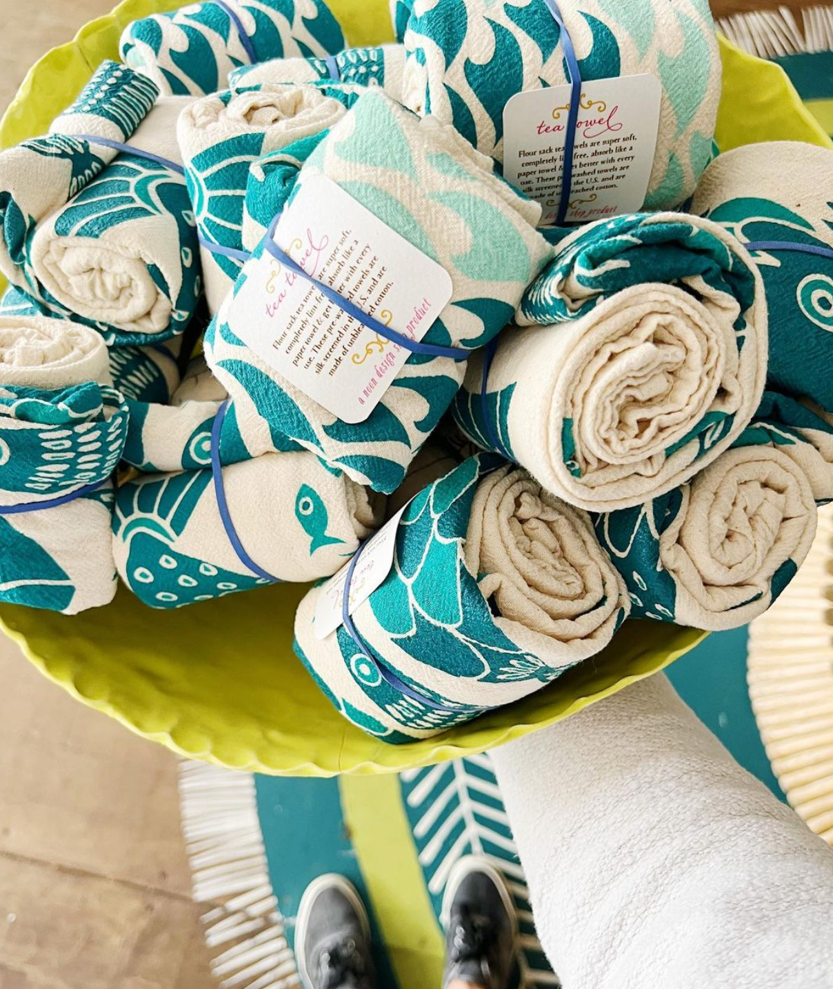 A green bowl full of blue and white fish printed tea towels