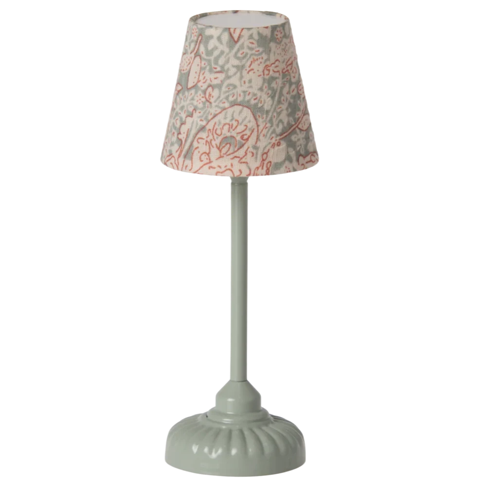 A vintage style floor lamp with a mint green base and a patterned shade, depicting a mouse hole design.