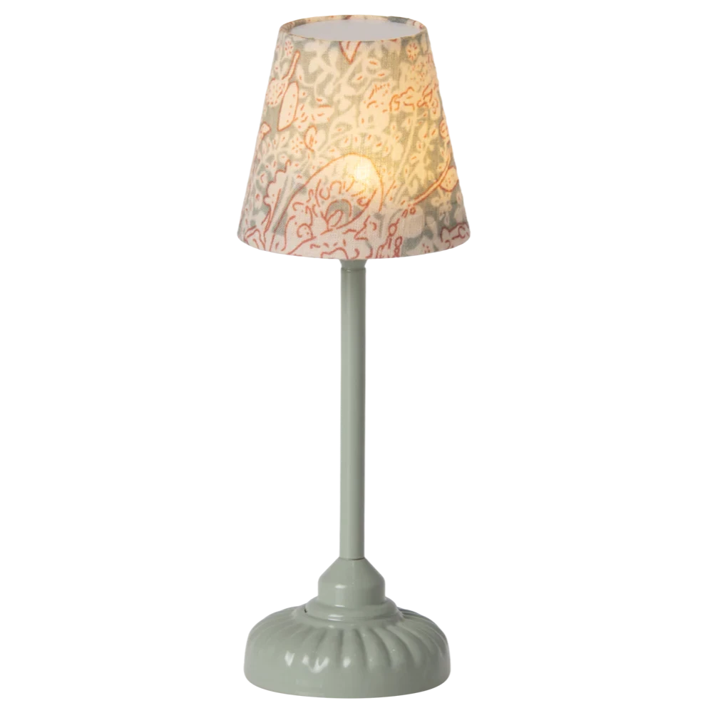 A vintage style floor lamp with a mint green base and a patterned shade, depicting a mouse hole design.