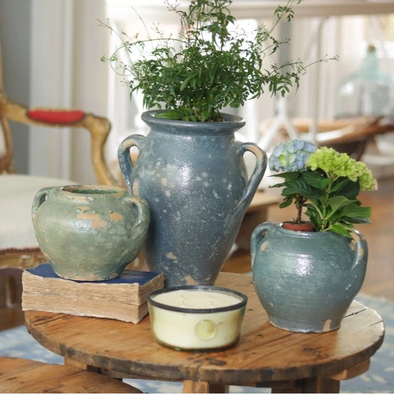 A room with a chair and wooden tables, with blue confit pots in the foreground. 