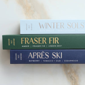 Three scented candles labeled 'Winter Solstice', 'Fraser Fir', and 'Apres Ski' on a light background.