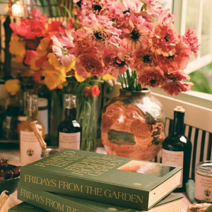 Two Fridays from the Garden books, with a bouquet of daisies and bottles of balsamic and olive oil in the background