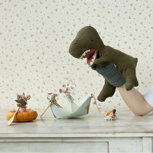 Dinosaur and mouse plush toys on a table with a floral wallpaper background